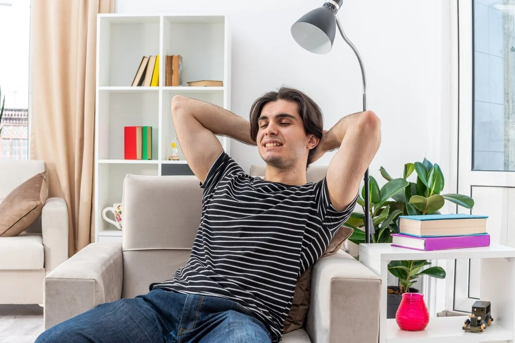 young man casual clothes happy positive relaxing spending weekend sitting chair light ventilation air living room